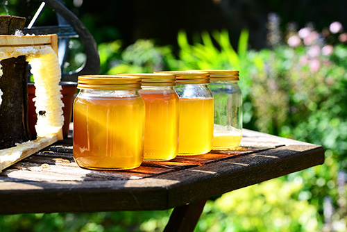 A row of jars filled with honey, out on a table in the sunshine. Unlock the potential with our tidy up tricks.